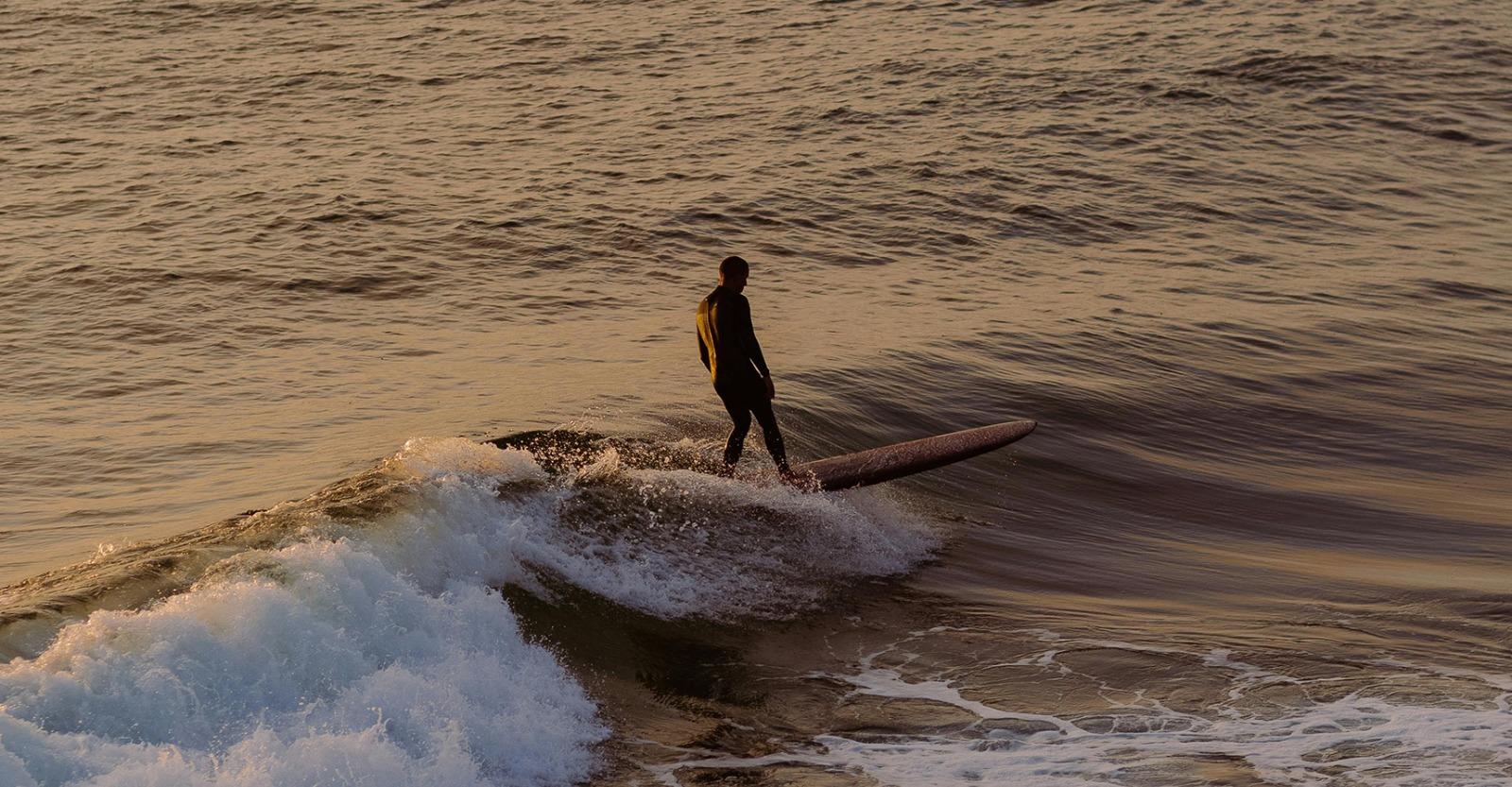 Man surfing a wave at sunset