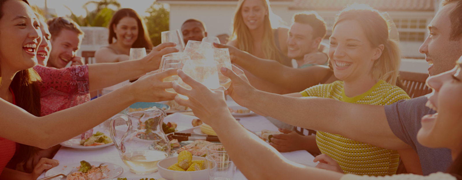 People sitting at dining table smiling and cheersing beverages